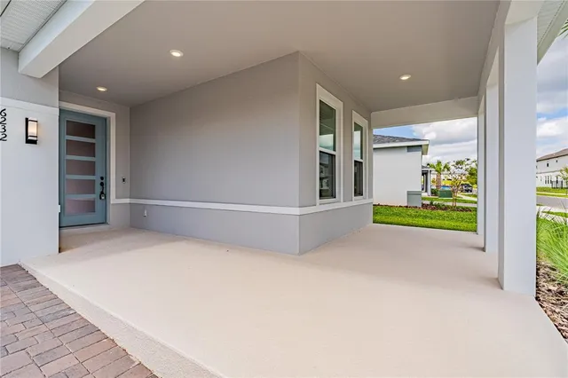 an empty room with floor to ceiling windows and kitchen view