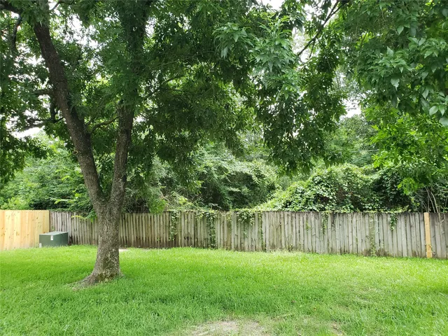 a backyard of a house with lots of plants and large trees