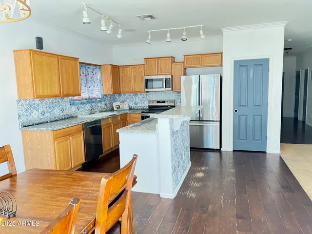 a kitchen with stainless steel appliances granite countertop a refrigerator a sink dishwasher a stove and a microwave oven on dining table with wooden floor