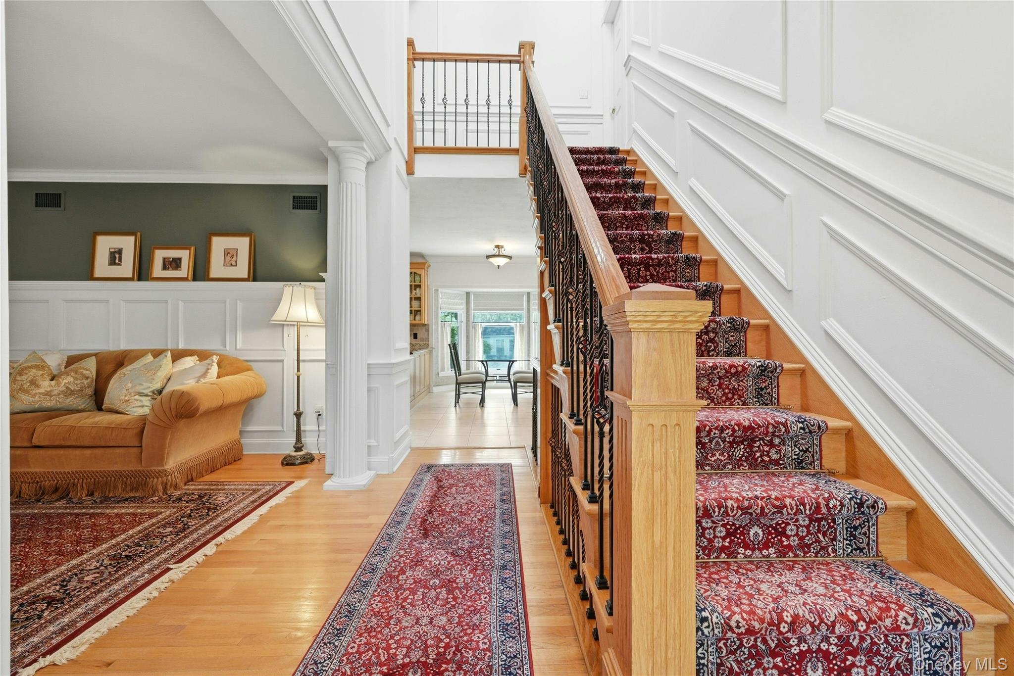 6 Thunder Road Miller Place, NY 11764 - Photo 13 of 50 Another View Of The Exquisite Formal Entrance Foyer Offering A Stunning Two Story Stairway To To The Second Level With Custom Oak & Wrought Iron Bannisters, Railings, Spindles & Stairs, Magnificent Fully Floor To Ceiling Box Paneled/Wainscoted Walls, Beautiful Hardwood Floors, A Two Column Entrance Into The Formal Living Room & Then Opens Into The Kitchen, Dinette And Den/Family Room.