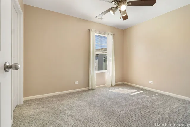 an empty room with a ceiling fan and carpet