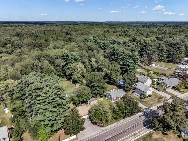 an aerial view of residential houses with outdoor space and trees