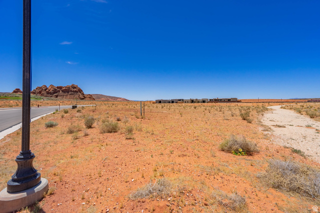 3306 South Endless Trail, Unit 33 Hurricane, UT 84737 - Photo 18 of 27 Expansive undeveloped land featuring a paved road, a light post with a concrete base, and distant rock formations
