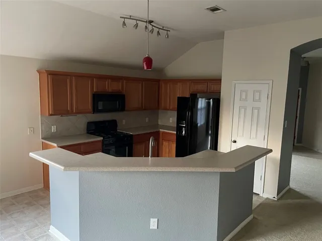 a kitchen with stainless steel appliances kitchen island granite countertop a refrigerator and a stove top oven