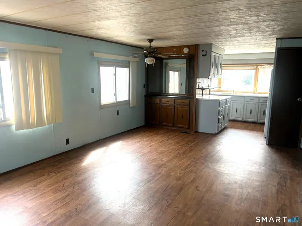 a view of empty room with wooden floor and fan