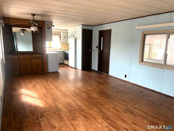an empty room with wooden floor and a kitchen