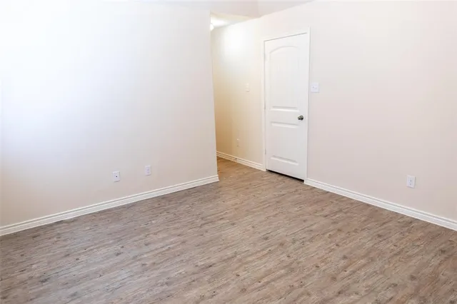 an empty room with wooden floor and mirror
