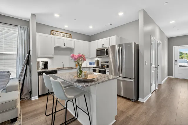 a kitchen with refrigerator and wooden floor