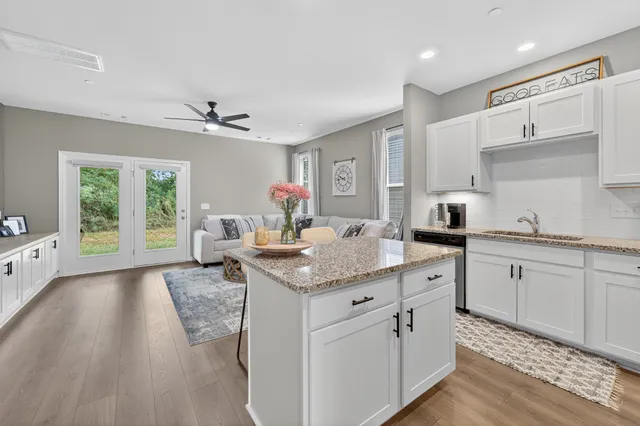 a kitchen with granite countertop a sink cabinets and wooden floor