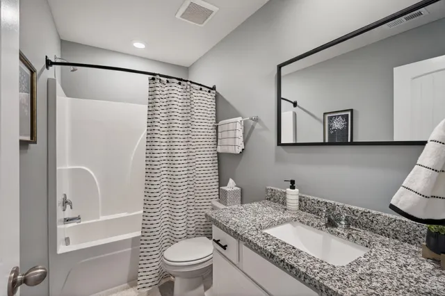 a bathroom with a granite countertop sink toilet and shower