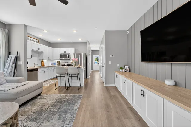 a large living room with stainless steel appliances a couch a flat screen tv and a view of living room