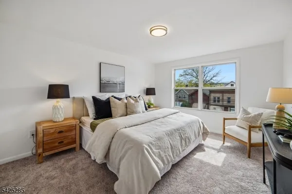 a bedroom with bed a night stand and a large window