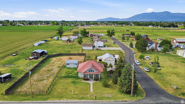 5264 West 5500th Street South Hooper, UT 84315 - Photo 4 of 38 Aerial perspective showcasing a residential property with a red-roofed home, surrounded by green fields and distant mountains