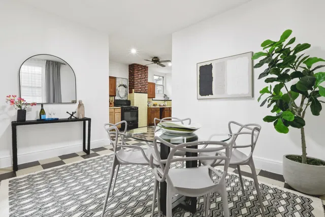 a living room with furniture a potted plant and a kitchen view