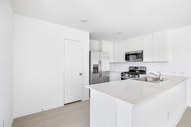 a kitchen with stainless steel appliances white cabinets and a stove a refrigerator with wooden floor