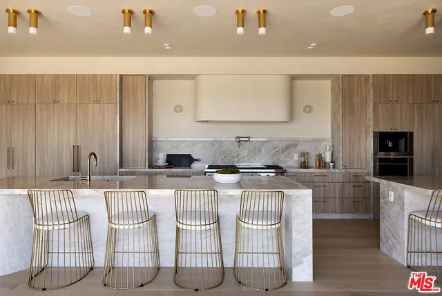 a living room with couches and kitchen view with wooden floor