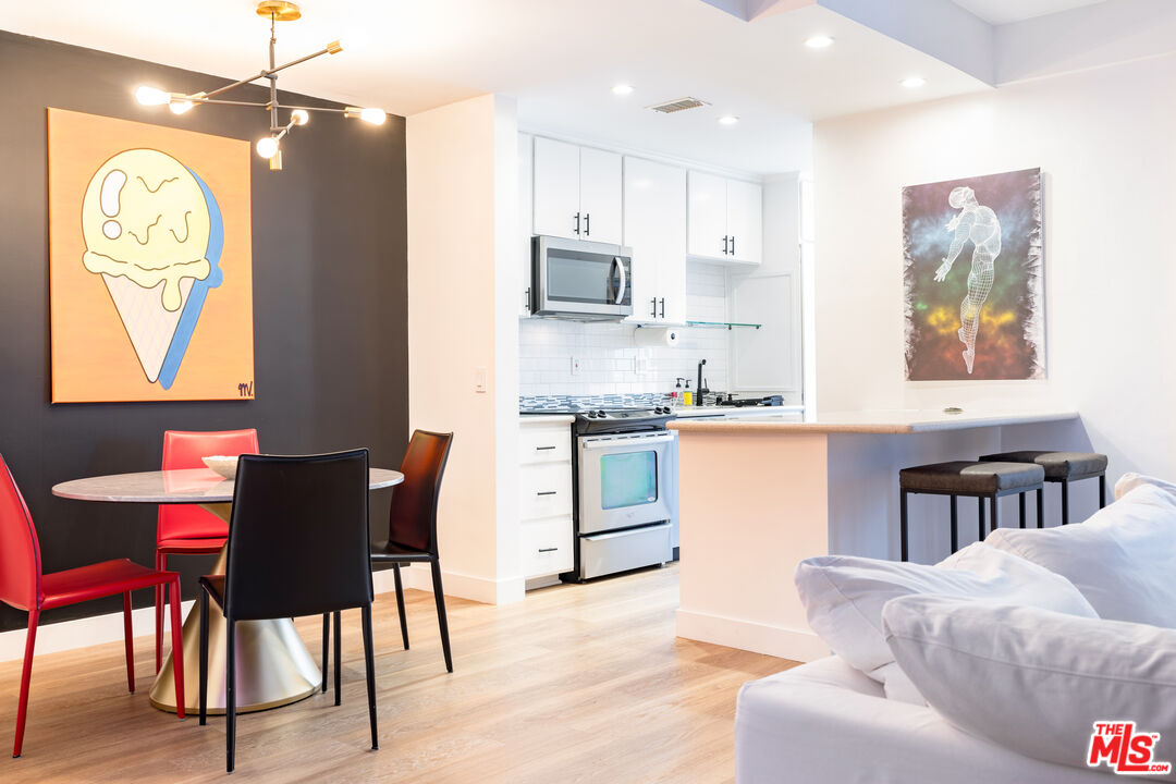 7250 Franklin Avenue, Unit 512 Los Angeles, CA 90046 - Photo 10 of 28 a kitchen with stainless steel appliances granite countertop a stove a refrigerator a dining table and chairs with wooden floor