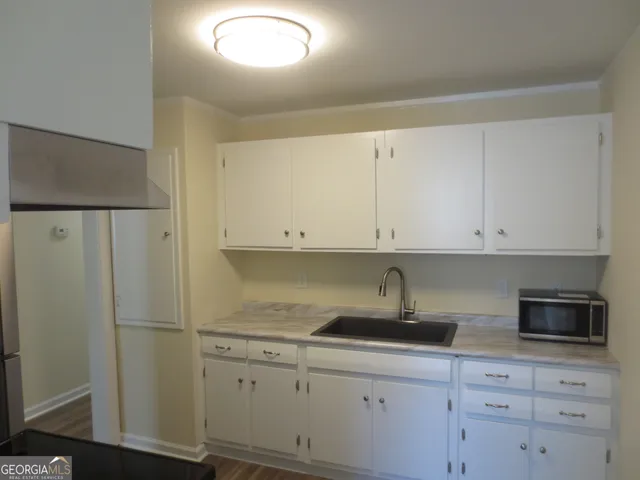 a kitchen with white cabinets and refrigerator