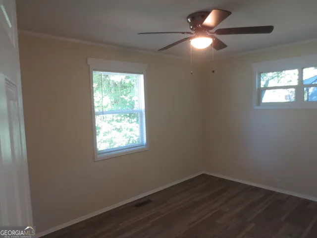 a view of an empty room with window and wooden floor