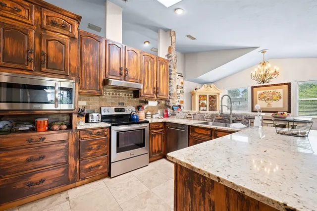 a kitchen with stainless steel appliances granite countertop a stove a sink dishwasher and cabinets with wooden floor