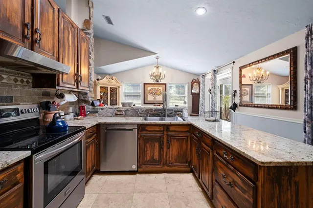 a kitchen with stainless steel appliances granite countertop a stove a sink and a microwave