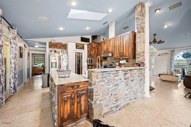 a kitchen with stainless steel appliances kitchen island granite countertop a refrigerator and a stove
