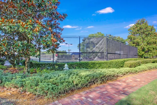 a view of a tennis ground with large trees