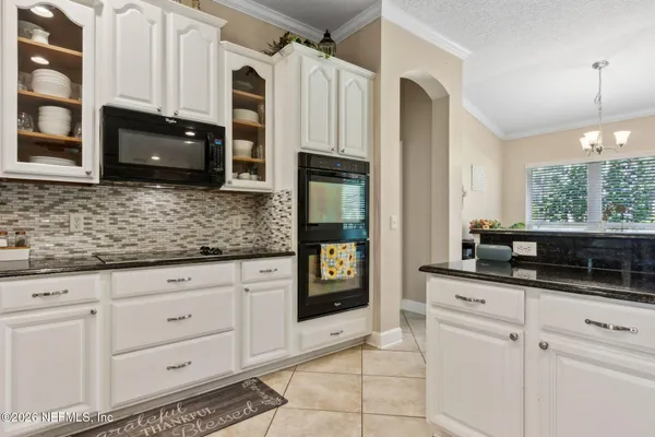 a kitchen with granite countertop a sink and white cabinets