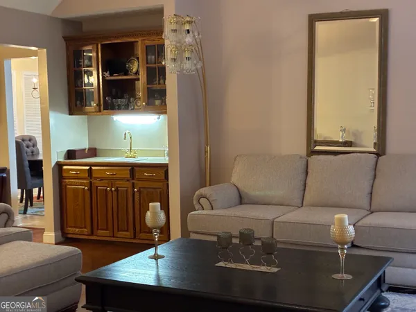 a living room with furniture two large window and wooden floor