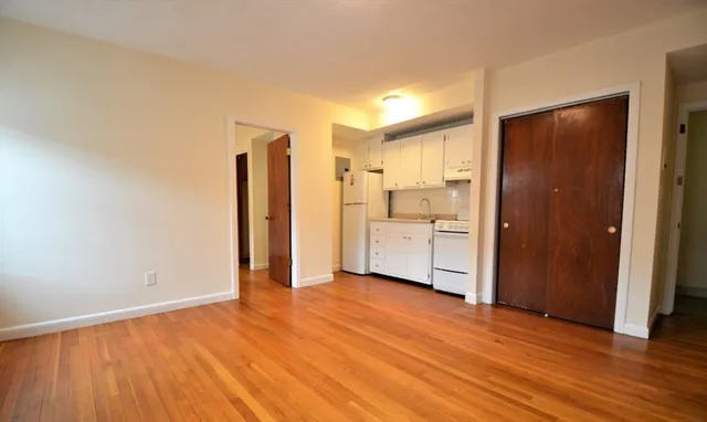 a view of a kitchen with a refrigerator and wooden floor