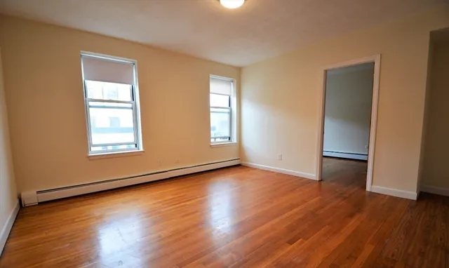 a view of an empty room with wooden floor and a window