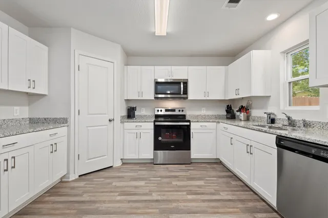 a kitchen with granite countertop a refrigerator stove top oven and sink