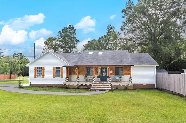 a front view of house with yard and trees in the background