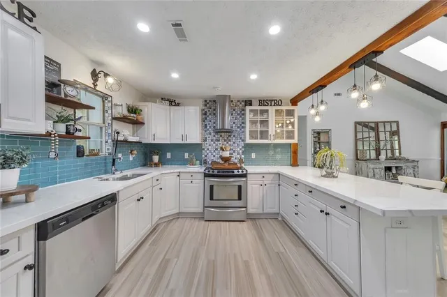 a large kitchen with stainless steel appliances granite countertop a lot of counter space and wooden floors