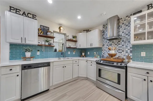 a kitchen with stainless steel appliances granite countertop a stove and white cabinets