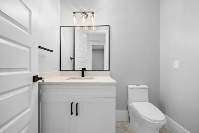 a bathroom with a toilet sink vanity and mirror