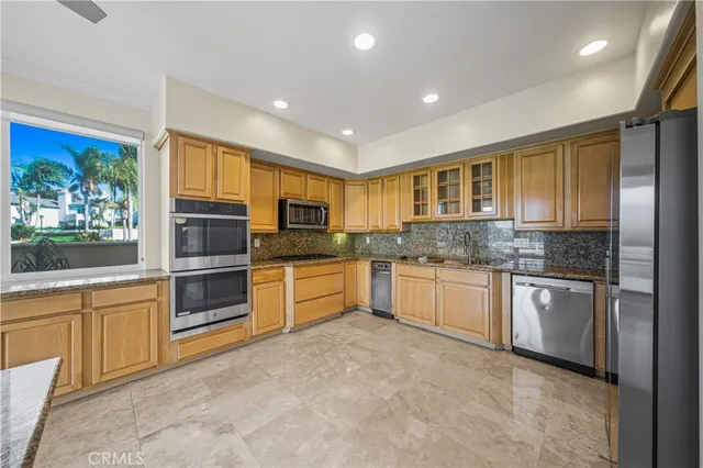 a kitchen with stainless steel appliances granite countertop a stove top oven a sink and dishwasher a refrigerator with wooden cabinets