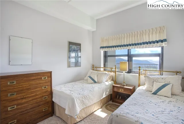 a bedroom with a bed and large windows