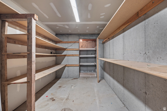 328 Heather Ridge Circle Sandy, UT 84070 - Photo 22 of 28 Spacious storage area featuring extensive built-in shelving, concrete walls, concrete flooring, and ceiling-mounted strip lighting