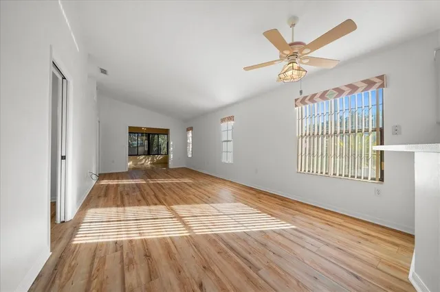 a view of empty room with wooden floor and fan
