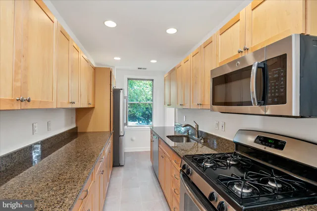a kitchen with stainless steel appliances granite countertop a stove and a microwave