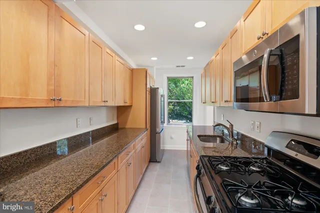 a kitchen with stainless steel appliances granite countertop a stove a sink and a microwave