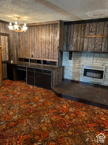 108 South Road Montpelier, ID 83254 - Photo 15 of 36 Kitchen featuring heating unit, a glass covered fireplace, wood walls, and a chandelier