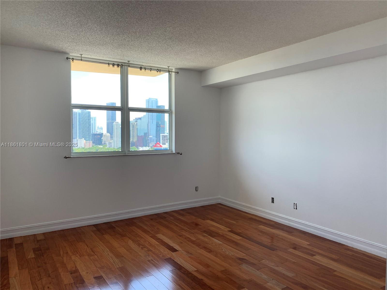 2475 Brickell Avenue, Unit 2504 Miami, FL 33129 - Photo 19 of 32 an empty room with wooden floor and windows