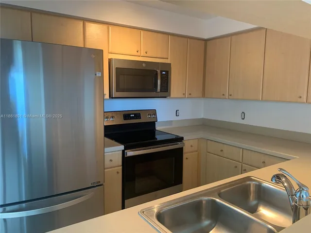 a view of kitchen with refrigerator and white cabinets
