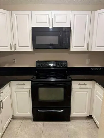 a kitchen with granite countertop white cabinets and black appliances
