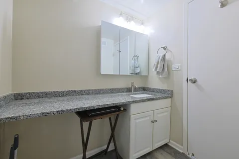 a bathroom with a granite countertop sink a toilet and mirror