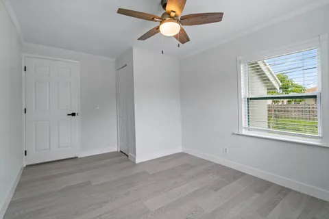 an empty room with wooden floor a ceiling fan and windows