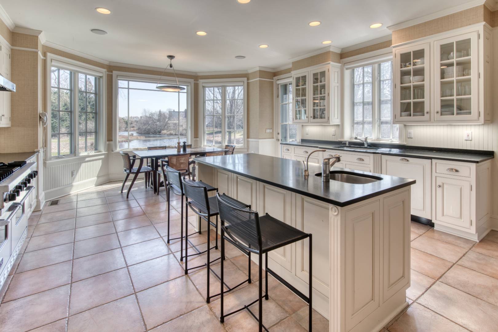 181 Parsonage Pond Road Sagaponack, NY 11962 - Photo 13 of 25 a kitchen with stainless steel appliances granite countertop a stove a sink a table and chairs in it