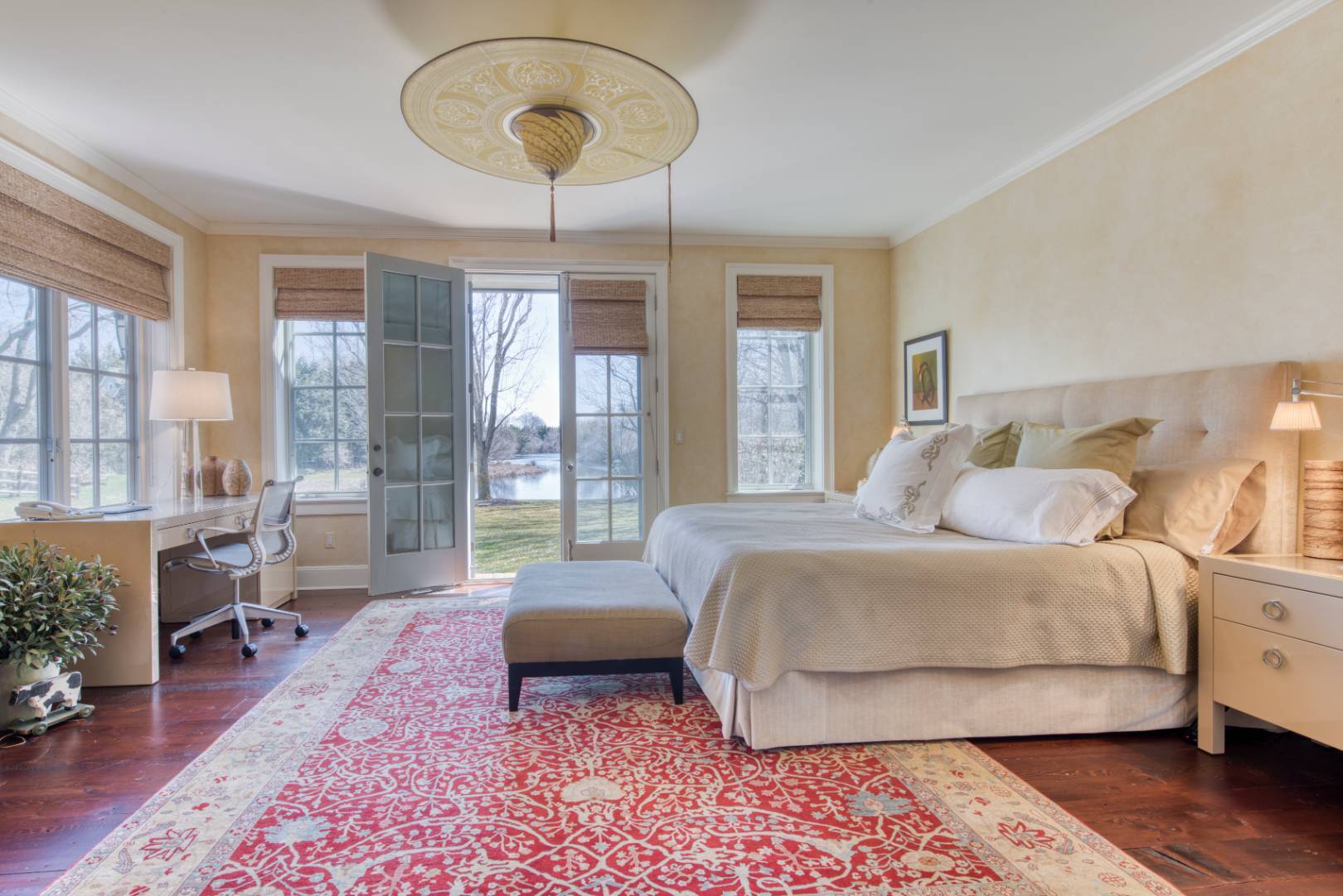 181 Parsonage Pond Road Sagaponack, NY 11962 - Photo 19 of 25 a spacious bedroom with a bed a chandelier and a large window